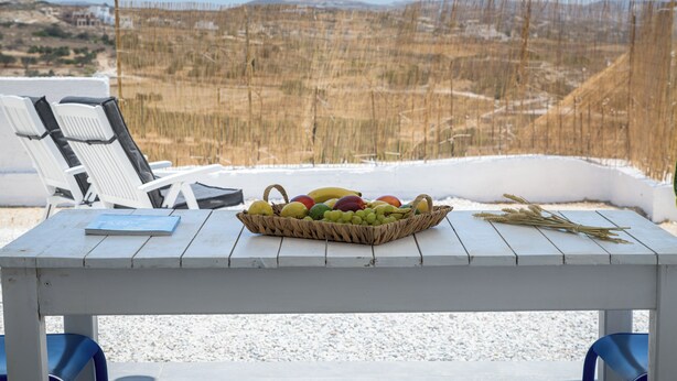 A table with a fruit basket, a book, and a view of a snowy landscape.