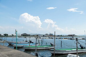 Un puerto deportivo con varias embarcaciones amarradas, un muelle de hormigón y un cielo despejado con nubes.