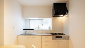 A compact kitchen with a window, a stove, and a dishwasher. - Destiny Seaside Village (Sakaiminato)