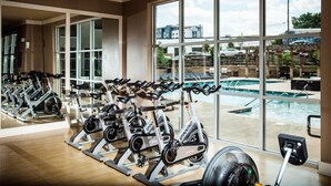 A gym with stationary bikes and a view of a swimming pool through large windows. - Stylish 2-bedroom in the Gulch - Walk to Nashville's hot spots! (Nashville)