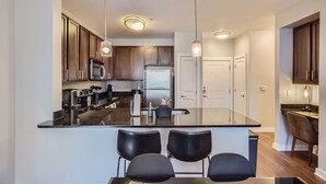 A modern kitchen with dark wooden cabinets, stainless steel appliances, and a central island with bar seating. - Stylish 2-bedroom in the Gulch - Walk to Nashville's hot spots! (Nashville)