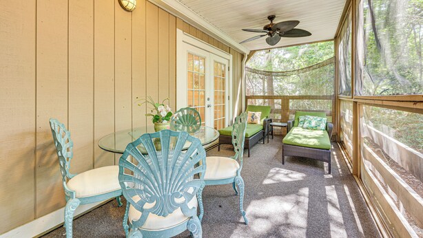 A covered porch with a glass table, chairs, and a bed. - Fernandina Beach Condo w/ Pool + Path to Beach! (Fernandina Beach)
