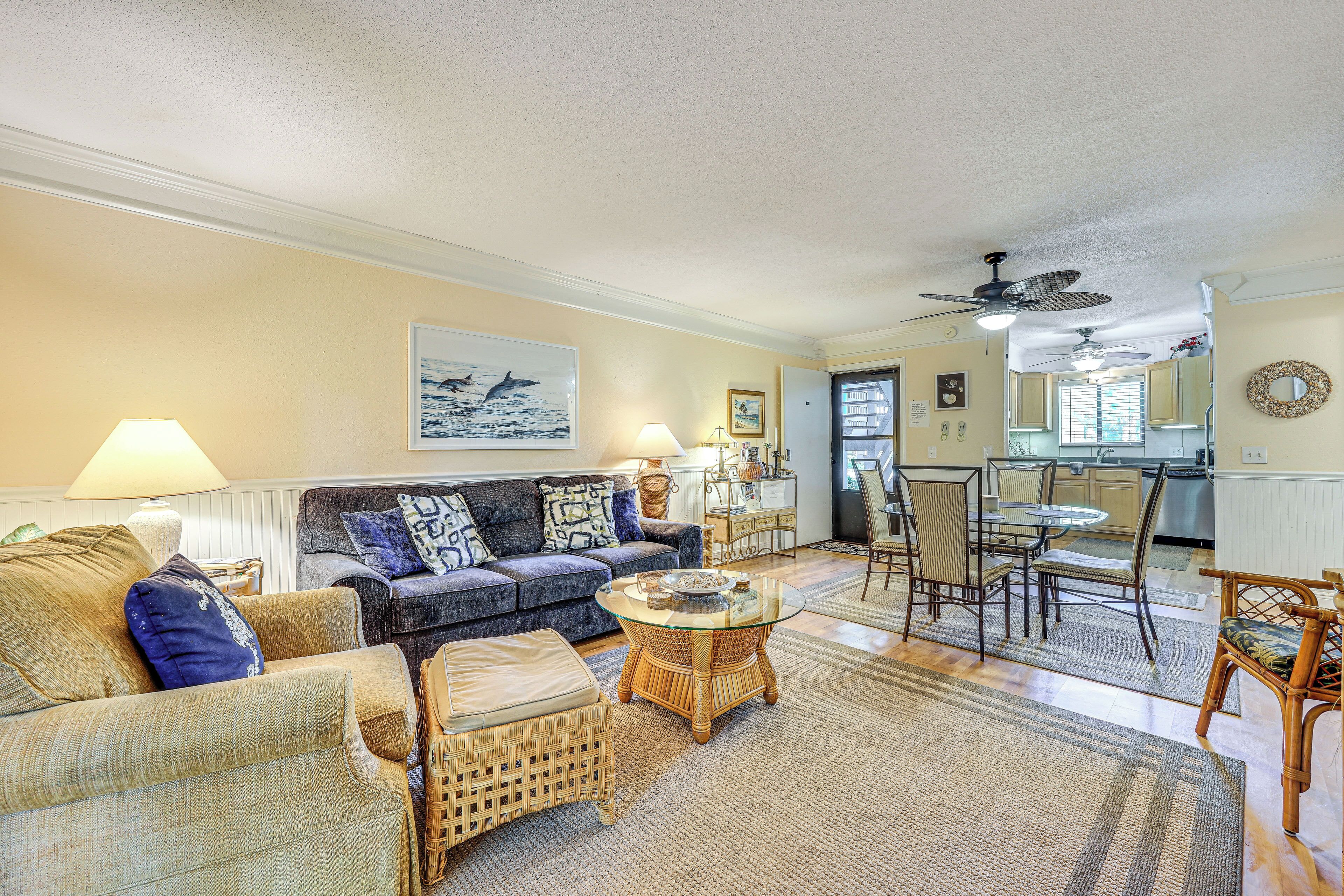 A living room with a sofa, a coffee table, and a dining area with chairs and a table.