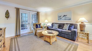 A living room with a sofa, armchairs, a coffee table, and a lamp. - Fernandina Beach Condo w/ Pool + Path to Beach! (Fernandina Beach)