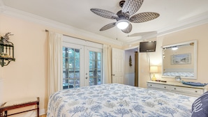 A bedroom with a large bed, a ceiling fan, a dresser, and a TV on the wall. - Fernandina Beach Condo w/ Pool + Path to Beach! (Fernandina Beach)