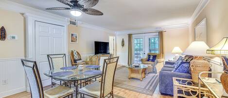 A spacious living room with a dining area, a sofa set, and a ceiling fan.