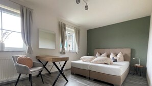 Une chambre à coucher avec un lit, un bureau, une chaise, un tapis moelleux et une fenêtre avec des rideaux.