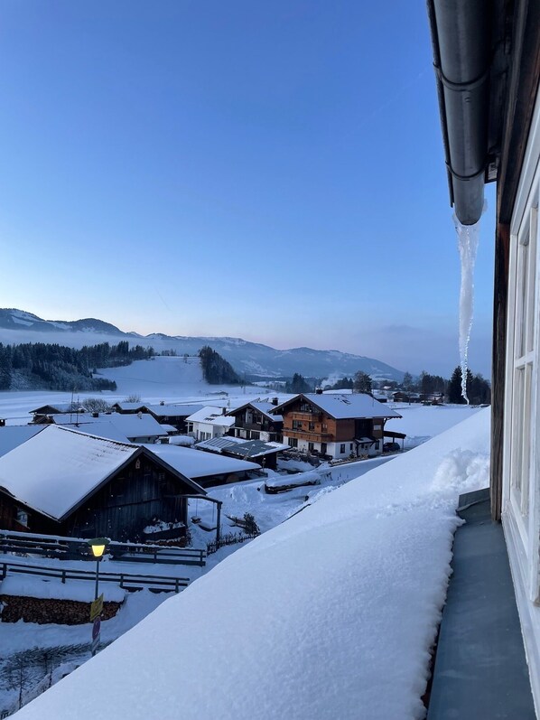 A snowy village with houses, a clear sky, and a view of distant mountains.
