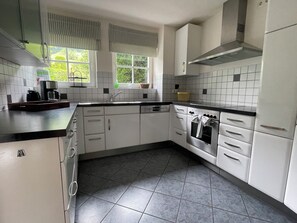 A kitchen with white cabinets, a black countertop, a coffee maker, and a window with blinds. - Charming vacation home in Oberstdorf-Reichenbach /Allgäu 4 bedrooms, 2 bathrooms (Oberstdorf)