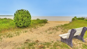 Un sendero de arena que lleva a un banco con vistas al mar.