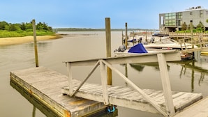 Un muelle de madera se extiende sobre una superficie de agua tranquila, con un barco llamado "Palm Beach" fondeado cerca.