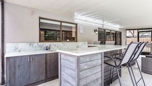Une cuisine dotée d’un plan de travail en marbre, de meubles en bois et d’une grande fenêtre.
