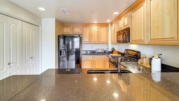 A kitchen with wooden cabinets, a stainless steel refrigerator, a stove, and a granite countertop. - Phoenix Condo ~ 1 Mi to Desert Ridge Marketplace! (Phoenix)