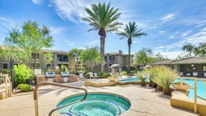 A pool area with a hot tub, lounge chairs, and palm trees. - Phoenix Condo ~ 1 Mi to Desert Ridge Marketplace! (Phoenix)