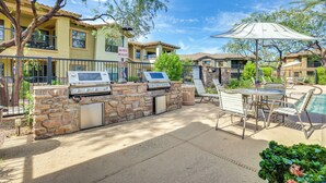 An outdoor patio with a stone barbecue, outdoor seating, and a pool. - Phoenix Condo ~ 1 Mi to Desert Ridge Marketplace! (Phoenix)