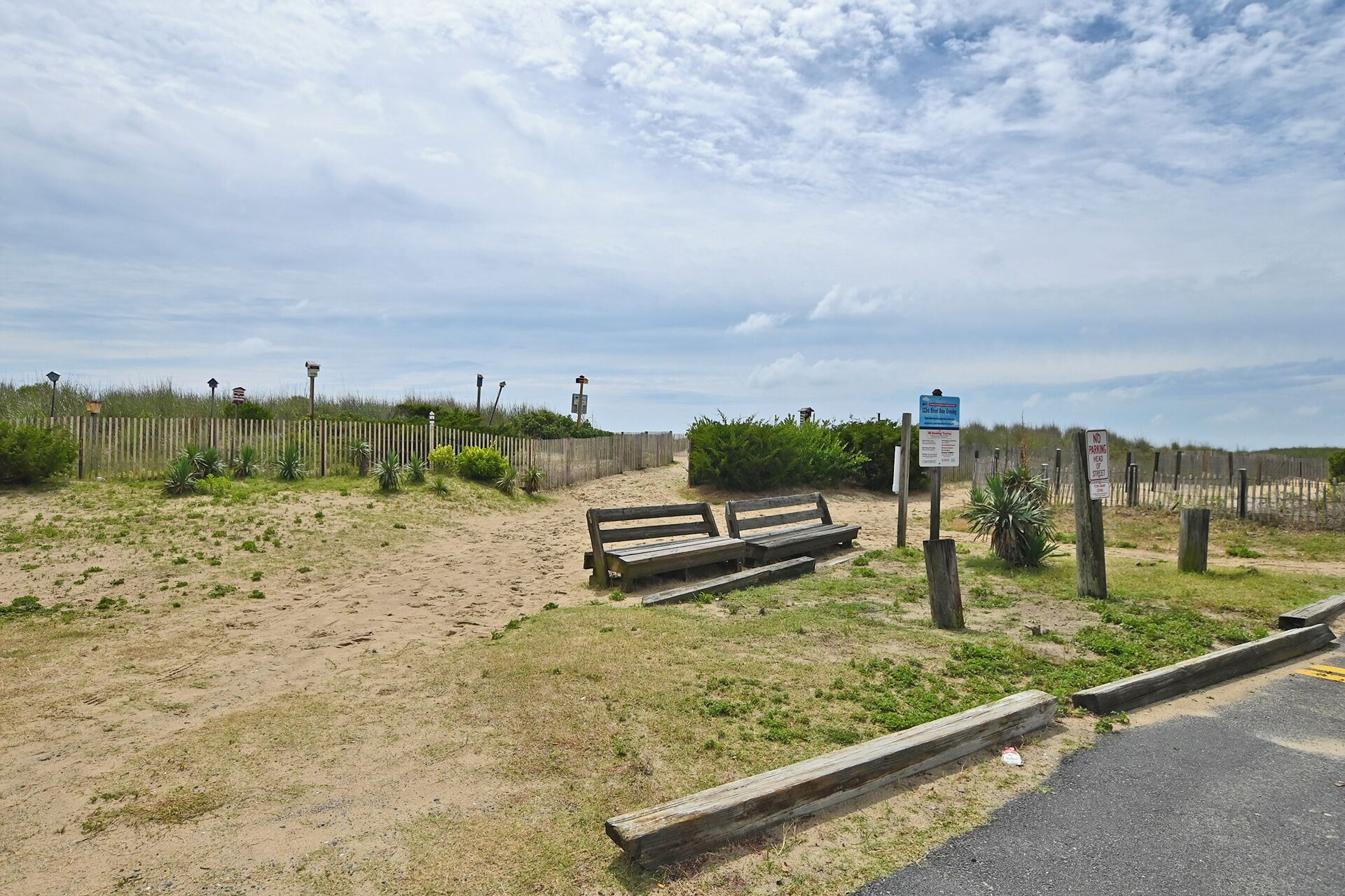 A sandy beach area with wooden benches and a wooden fence.