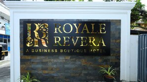 Une enseigne pour le Royale Revera, un hôtel-boutique de luxe, avec une façade en pierre et deux plantes en pot.