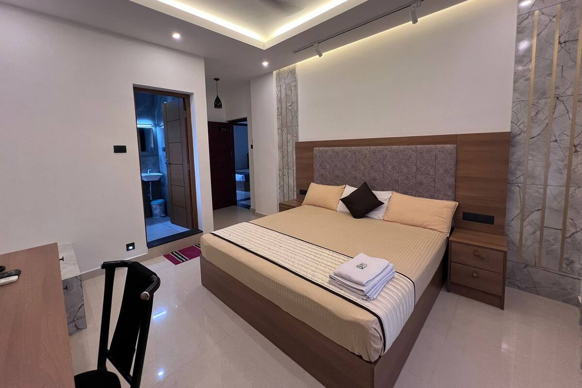 Un dormitorio moderno con una cama grande, mesitas de noche, un escritorio y un espejo.