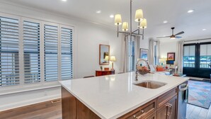 Een moderne keuken met een groot eiland, inbouwapparatuur en een stadszicht door grote ramen.