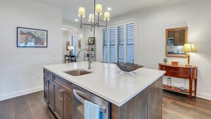 Een moderne keuken met een groot eiland, hanglampen en uitzicht op de eethoek.