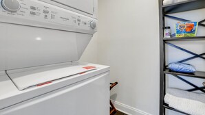 Eine Waschmaschine mit Frontlader, einer Hängebrett mit gefalteten Handtüchern und Waschmittel.