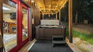 Ein Whirlpoolbereich mit Holzterrasse, einer Bank und Blick auf den umliegenden Wald.