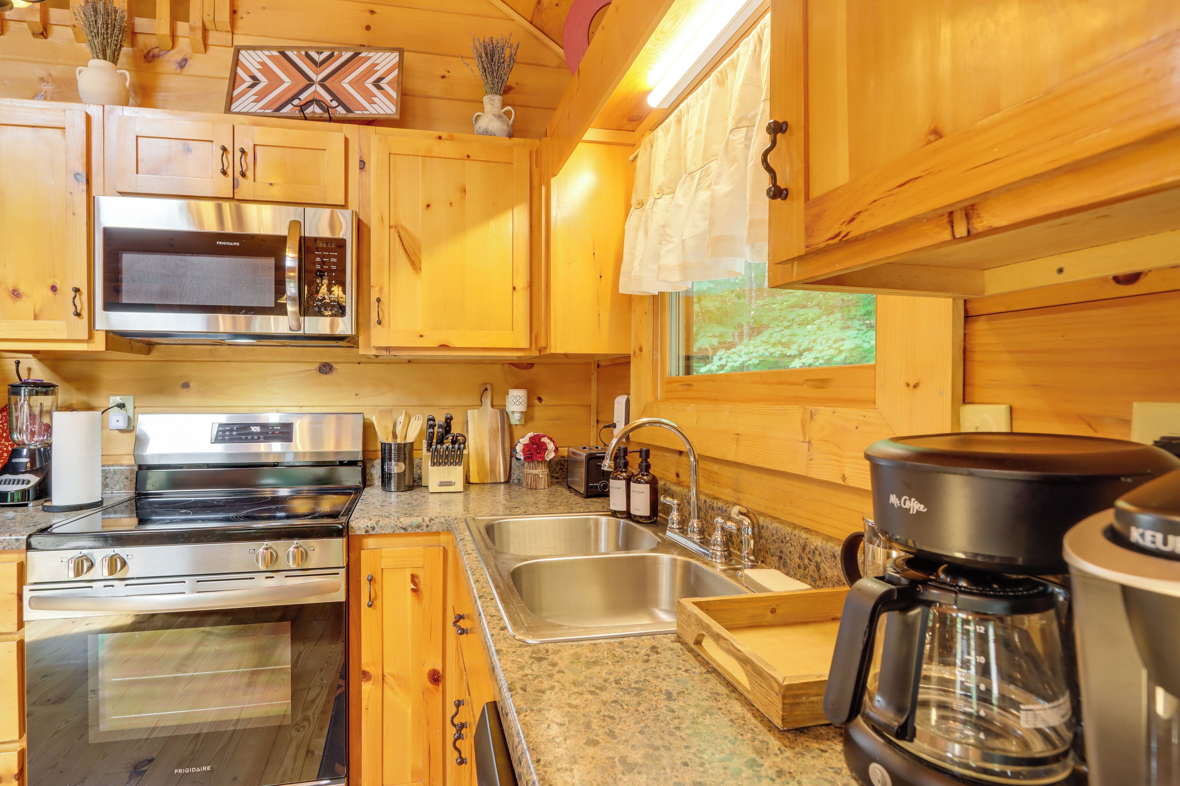 A compact kitchen with wooden cabinets, a stainless steel microwave, a stove, and a coffee maker.