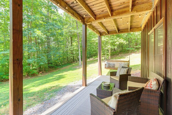 A covered porch with wicker furniture, a view of a forest, and a wooden deck. - Secluded Cabin: Hot Tub & 10 Mi to Blue Ridge (Epworth)