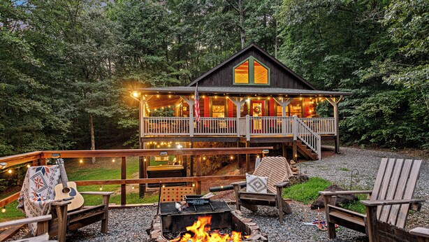 Eine Hütte mit einer Terrasse, Sitzgelegenheiten im Freien und einer Feuerstelle.