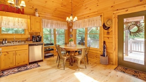 Ein Holzblockbau-Innenraum mit Küche, Essbereich und einer Terrasse.