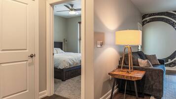 A bedroom with a bed, a ceiling fan, and a nightstand with a lamp.