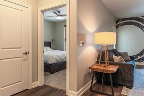A bedroom with a bed, a ceiling fan, and a nightstand with a lamp.
