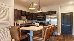 Una cocina moderna con armarios de madera oscura, electrodomésticos de acero inoxidable y una isla central con taburetes de bar.