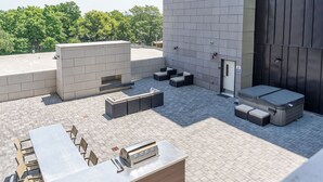 Terraza en la azotea con una larga mesa de comedor, mobiliario exterior y una parrilla.
