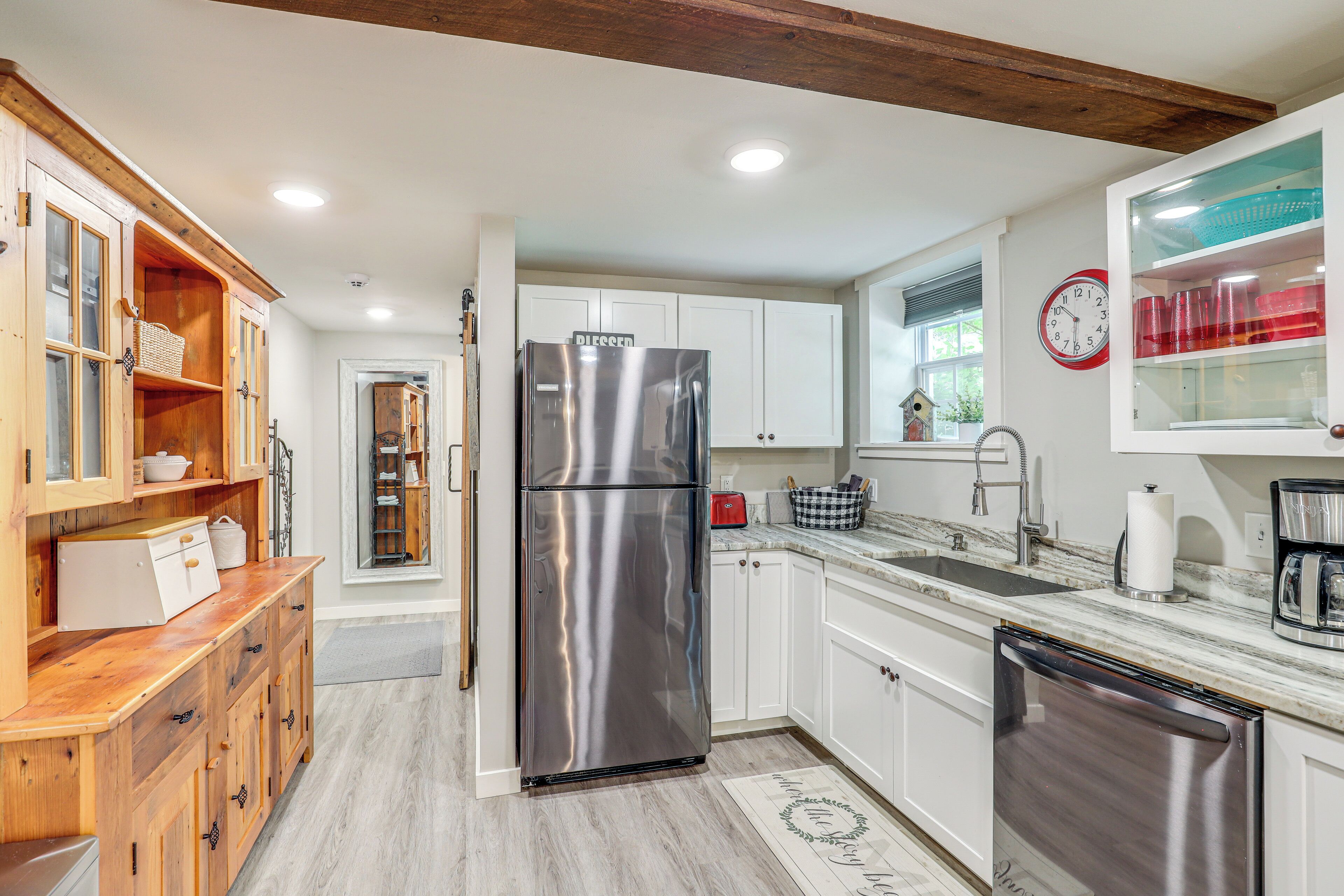 A modern kitchen with stainless steel appliances, wooden cabinetry, and a marble countertop.