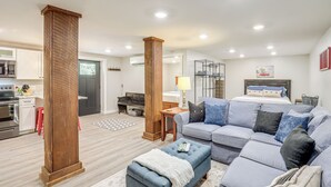 A modern living room with a sofa, ottoman, and wooden columns. - Walk to Downtown Weaverville: Quiet Apartment (Weaverville)