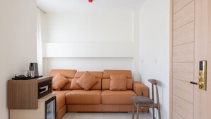 Un espace de vie compact comprenant un canapé, un fauteuil, un petit meuble et une porte.