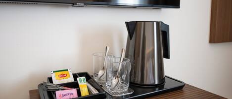 A tray with a coffee maker, glasses, and a tray with snacks and a bottle.