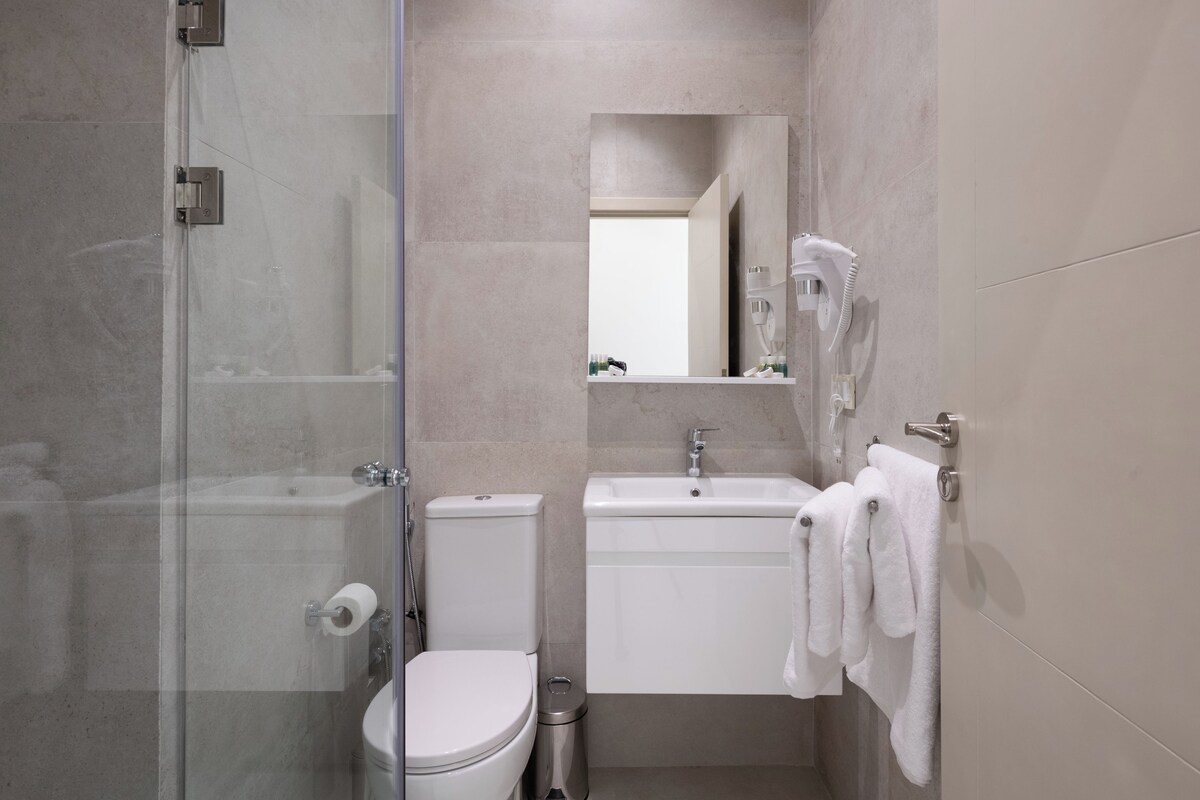 A modern bathroom with a glass shower enclosure, a toilet, a sink, and a mirror.