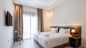 Une chambre d’hôtel moderne dotée d’un grand lit, de tables de chevet, d’un téléviseur à écran plat et d’une fenêtre avec des rideaux.