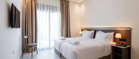 Een moderne hotelkamer met een groot bed, nachtkastjes, een flatscreen televisie en een raam met gordijnen.
