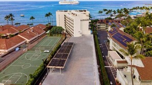 Un hotel con cancha de tenis, paneles solares y vista al océano.