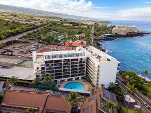 Un hôtel doté d’une piscine, entouré de verdure et offrant une vue sur l’océan.
