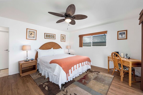 A bedroom with a bed, bedside tables, a desk, and a chair. - Hale Lani:Direct Oceanfront Massive Pool, Gated, Remodeled Beauty (KAILUA KONA)