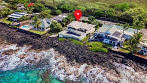 An aerial view of a coastal residential area with houses, a swimming pool, and a rocky shoreline. - Hale Lani:Direct Oceanfront Massive Pool, Gated, Remodeled Beauty (KAILUA KONA)