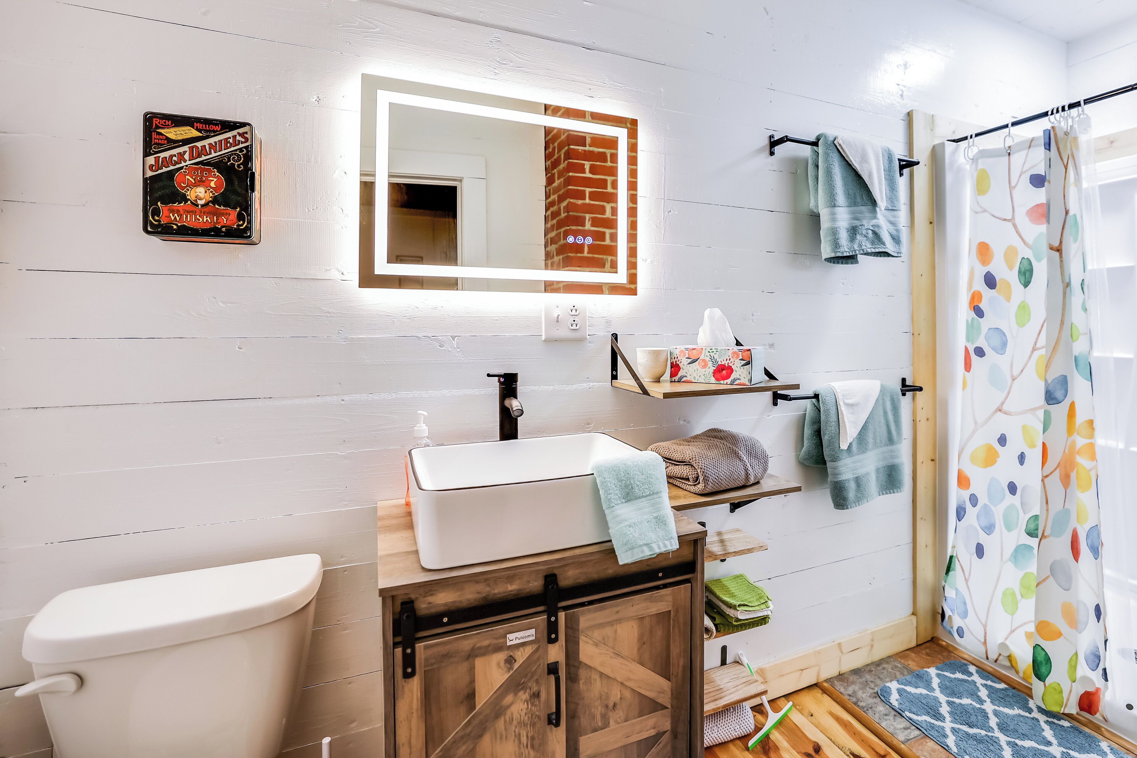 A bathroom with a white sink, a mirror, a toilet, and a shower curtain.