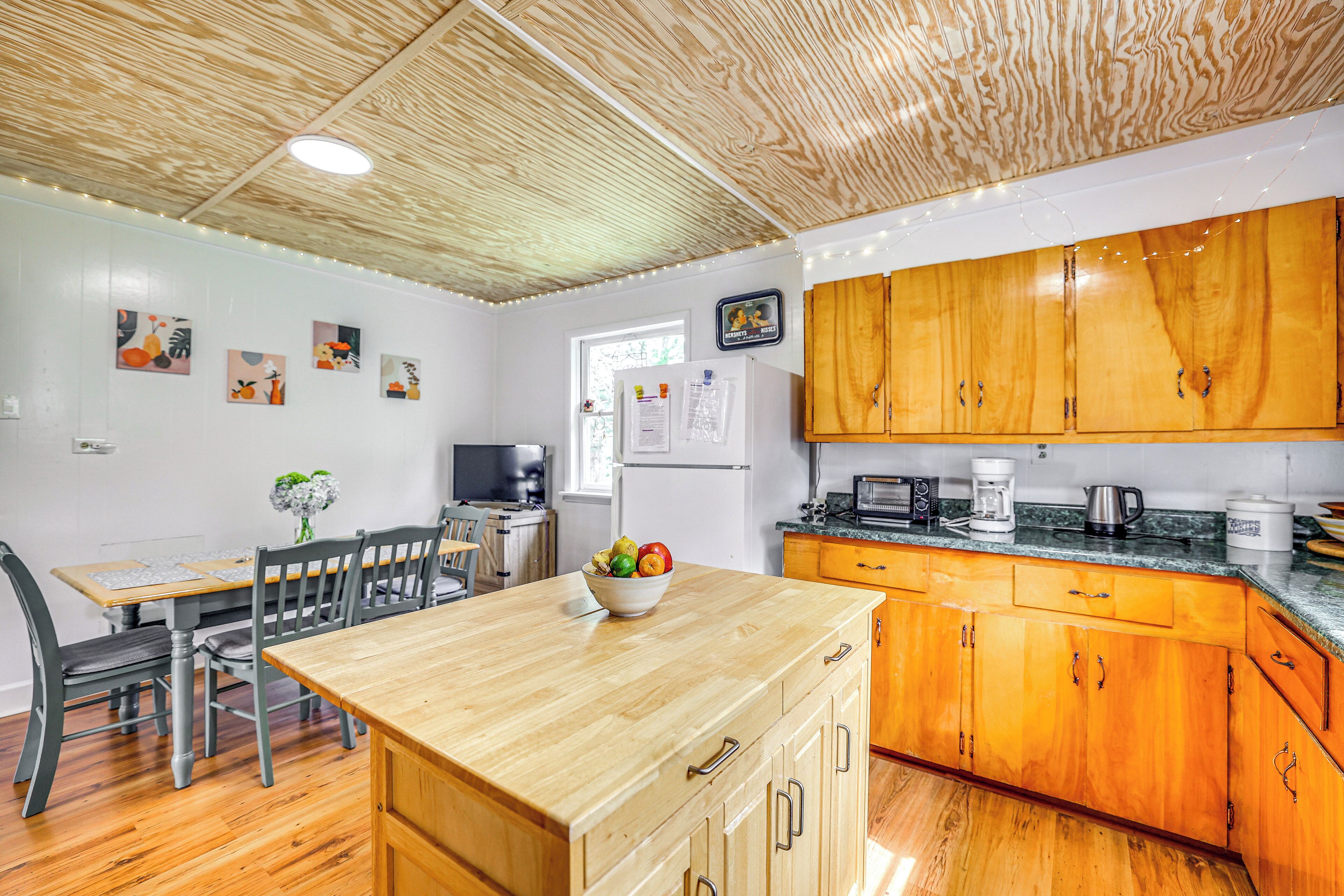 Une cuisine avec des meubles de rangement en bois, une table à manger et un réfrigérateur.