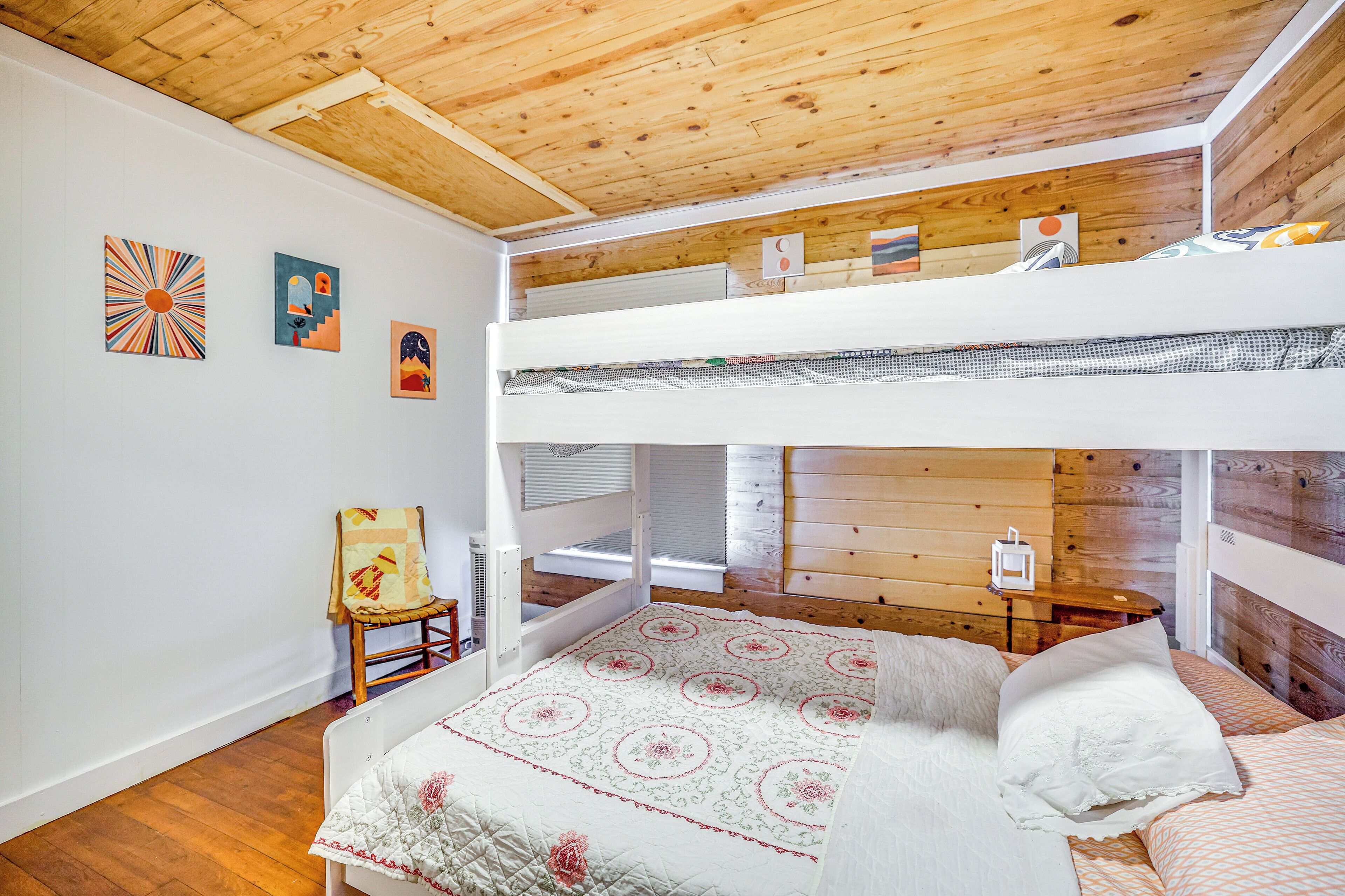 Habitació amb lliteres, sostre de fusta, mantell de llit acolxat i una cadira amb coixí.