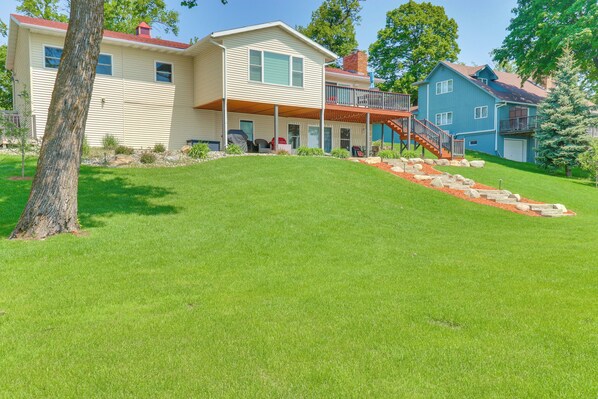 A two-story house with a covered porch, a staircase leading to a second level, and a well-maintained lawn.