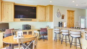 A kitchen with wooden cabinets, a large window, a dining table with chairs, and a bar area with stools. - Lakeside Alexandria Retreat w/ Deck + Boat Dock! (Alexandria)